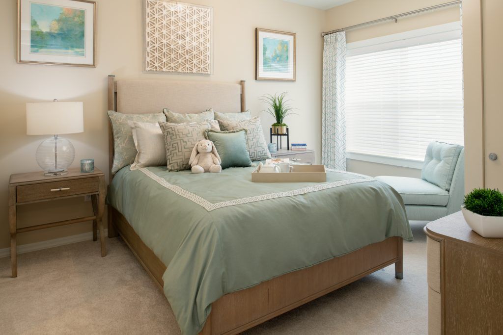 A cozy bedroom featuring a neatly made bed with decorative pillows, soft lighting, and elegant decor.