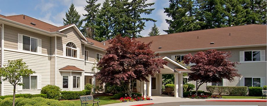 A residential building with a manicured landscape and trees surrounding the entrance.