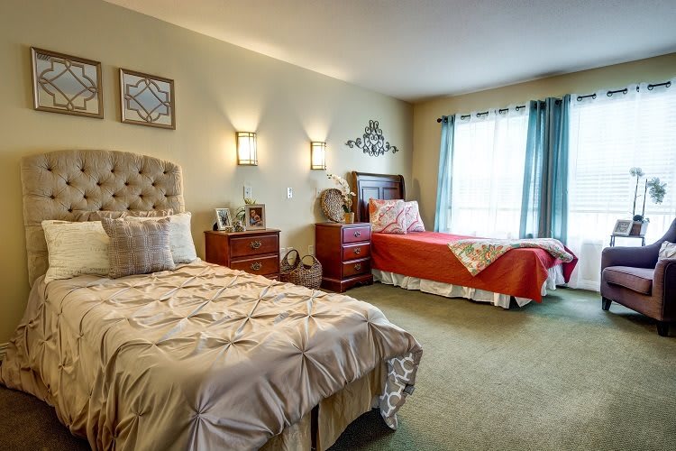 A cozy bedroom with two neatly made beds, warm lighting, and tasteful decorations.