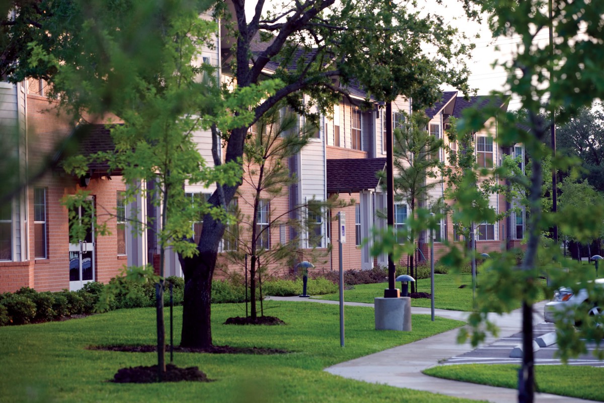 A peaceful suburban apartment complex with lush greenery and well-maintained landscaping.