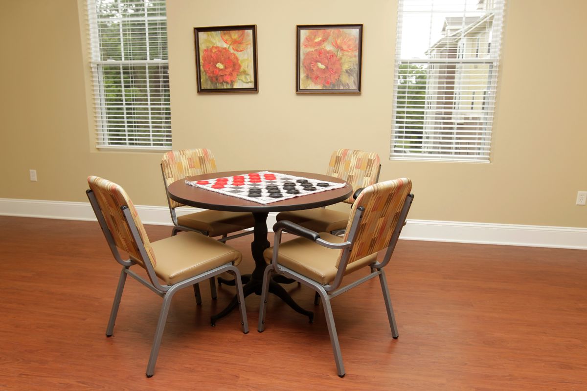 A cozy room with a round table and four chairs, featuring a checkers board setup.