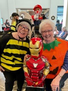 A cheerful group dressed in Halloween costumes, featuring a bee, pumpkin, and Iron Man.
