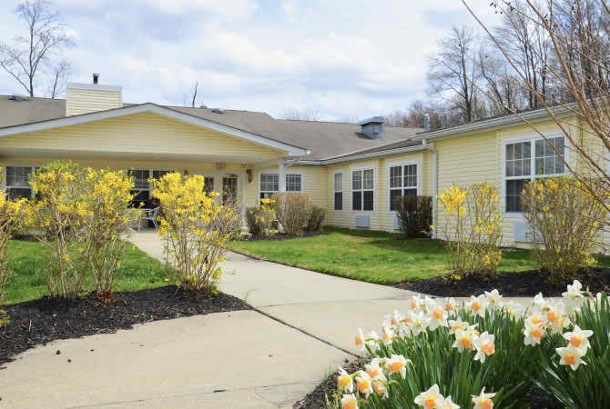A charming residential building with a garden full of spring flowers and a welcoming pathway.