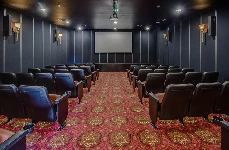 An empty movie theater with rows of comfortable seating and a large projection screen.