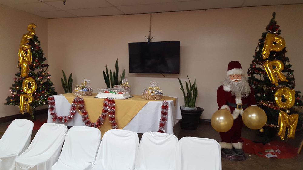 A festive indoor setting with a decorated table featuring cakes and an inflatable Santa Claus.
