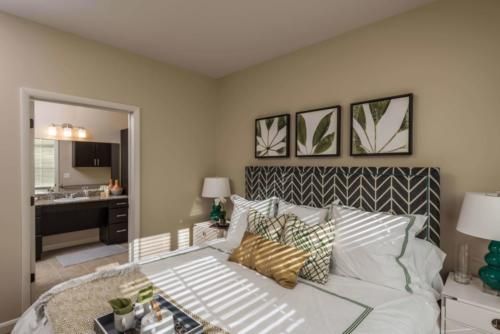 A well-decorated bedroom with a patterned headboard, framed leaf artwork, and cozy bedding.