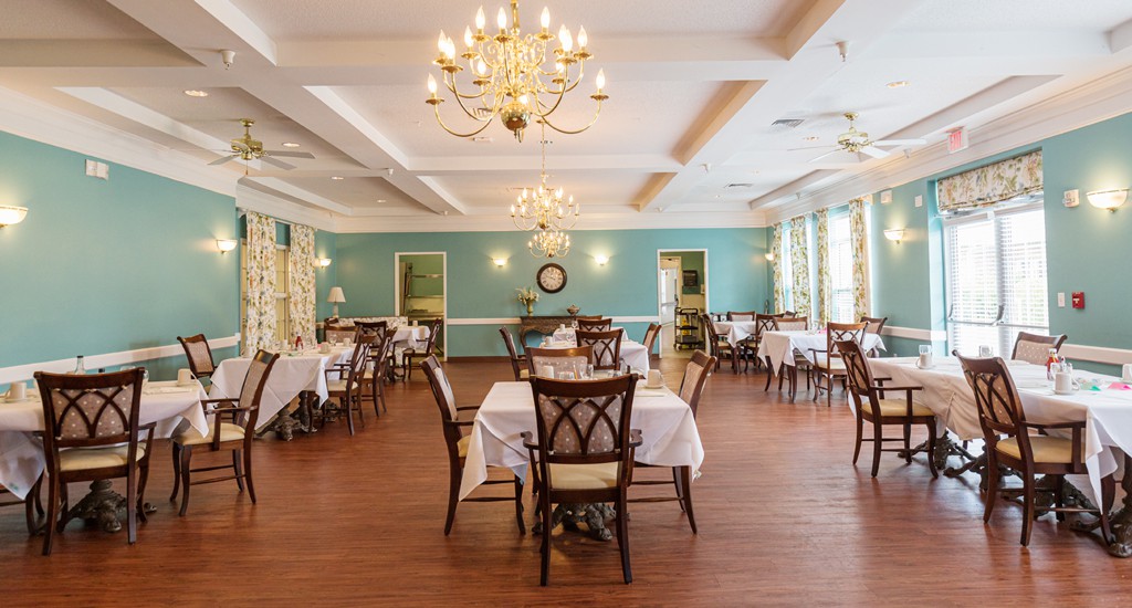 An elegant dining room with neatly arranged tables and chandeliers.