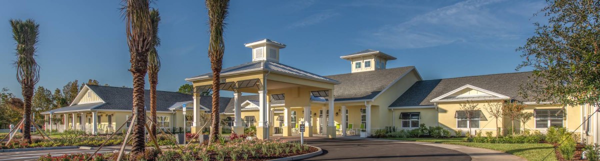 A well-designed building entrance with a covered area and landscaped surroundings under a clear blue sky.