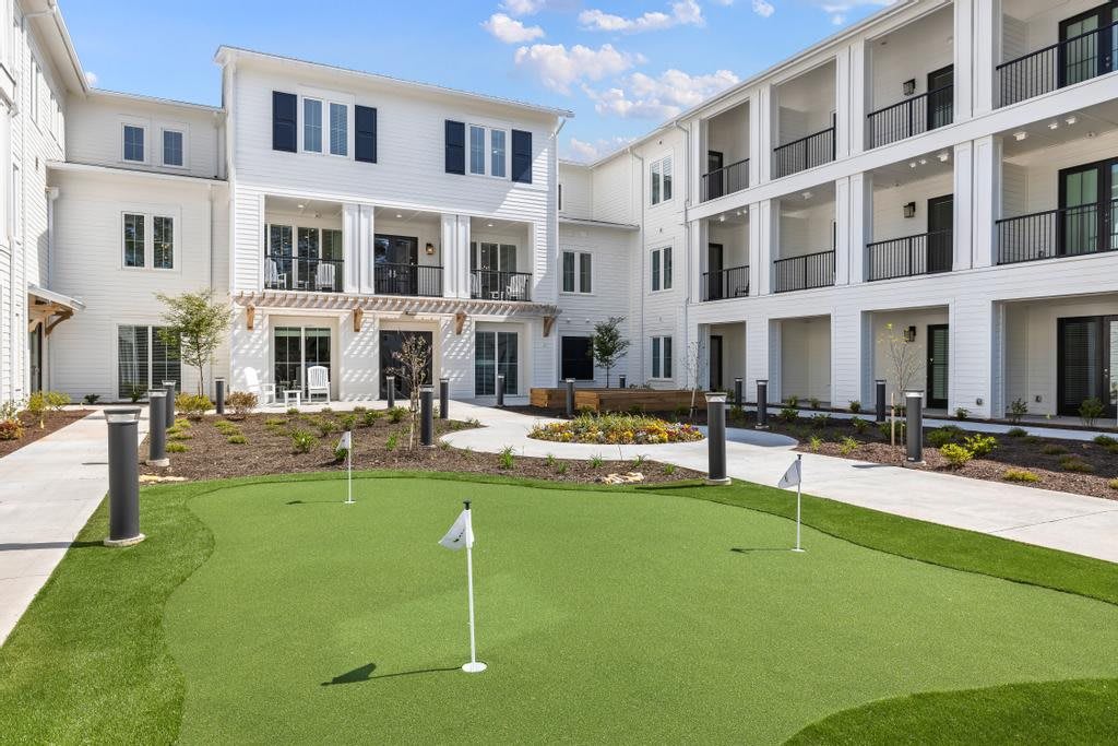 A modern apartment complex featuring a putting green and well-maintained outdoor landscaping.