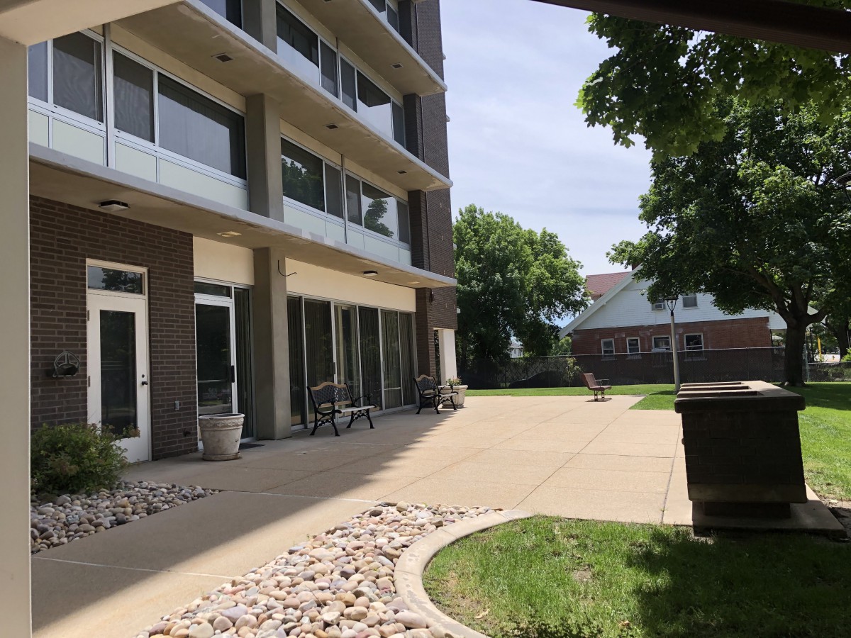 A view of an outdoor patio area next to a multi-story building with bicycles and greenery.