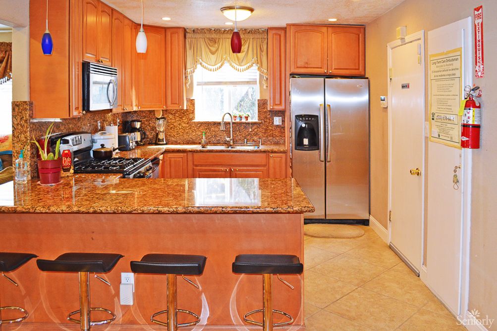 A modern kitchen featuring granite countertops, wood cabinets, and stainless steel appliances.