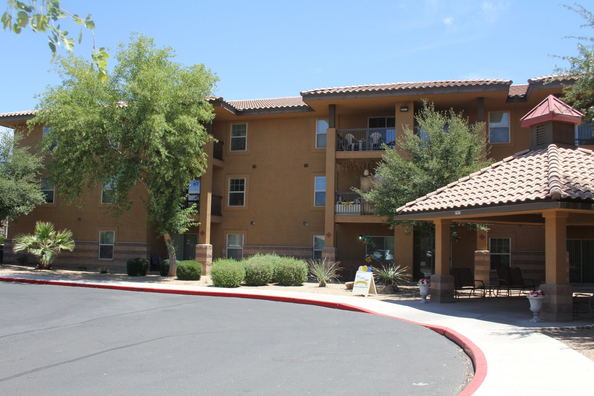 A view of an apartment building with a landscaped entrance area.