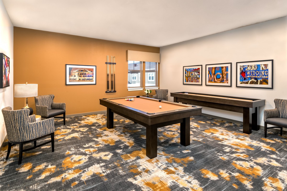 A modern game room featuring a pool table, art-adorned walls, and a comfortable seating area.