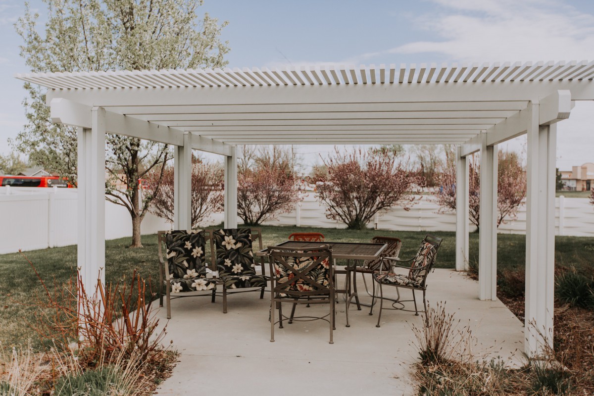 A beautiful outdoor patio with a pergola and decorative metal furniture.