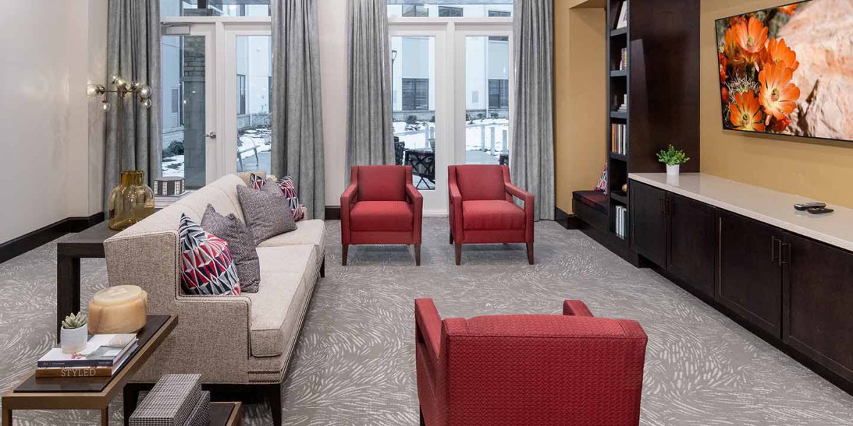 A cozy living room featuring red chairs, a beige sofa, and a bookshelf.