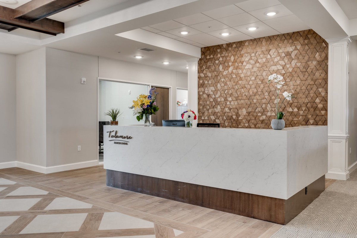 A modern and stylish office reception area with a white desk, decorative wall, and ambient lighting.