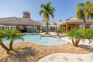 A luxurious vacation home with a swimming pool and palm trees in the backyard.