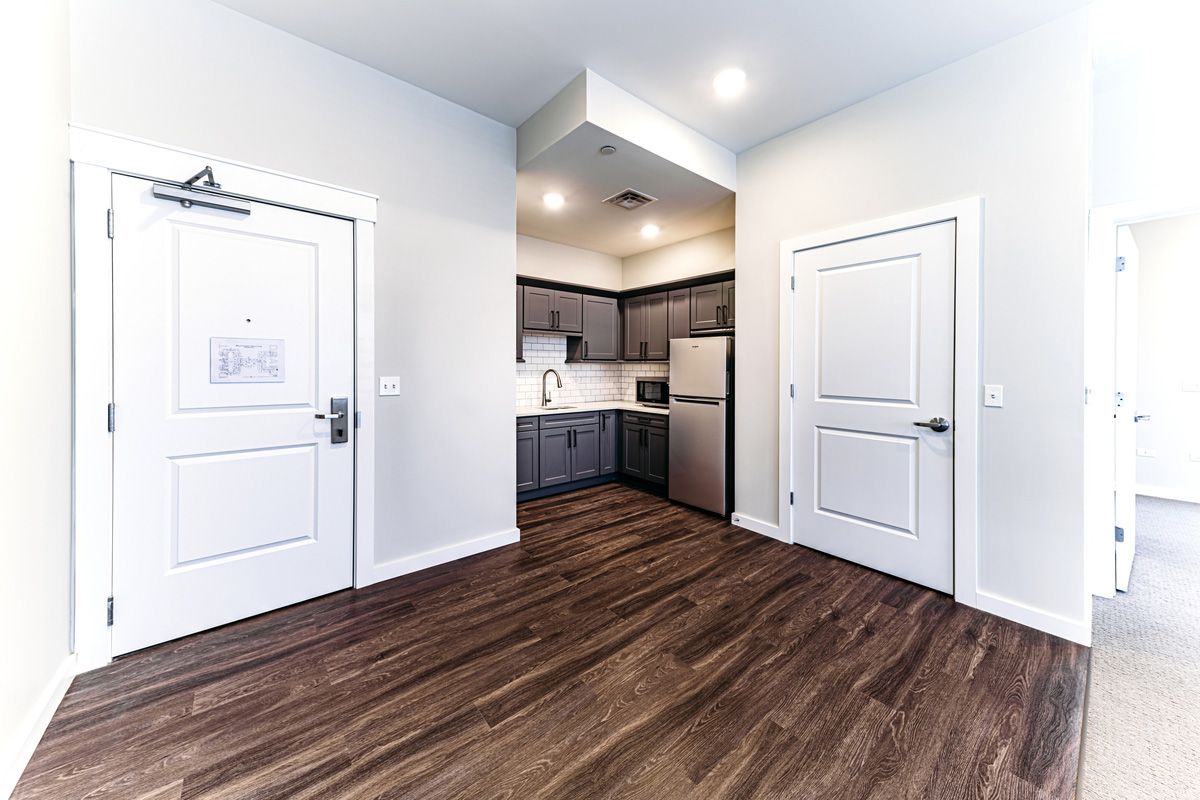 A modern kitchen in an apartment with wood flooring and stainless steel appliances.
