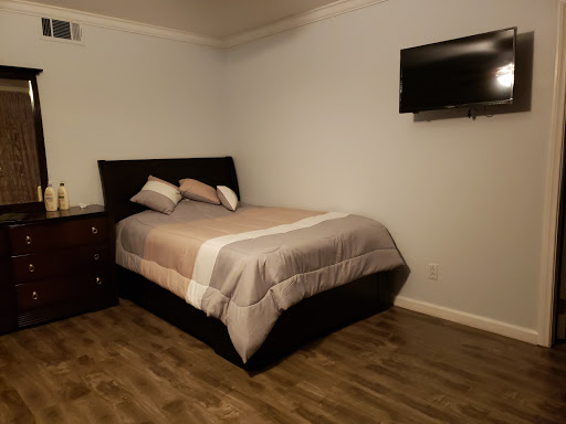 A cozy bedroom featuring a neatly made bed and a wall-mounted television.