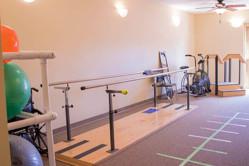 A rehabilitation studio featuring a ballet barre and various exercise equipment.
