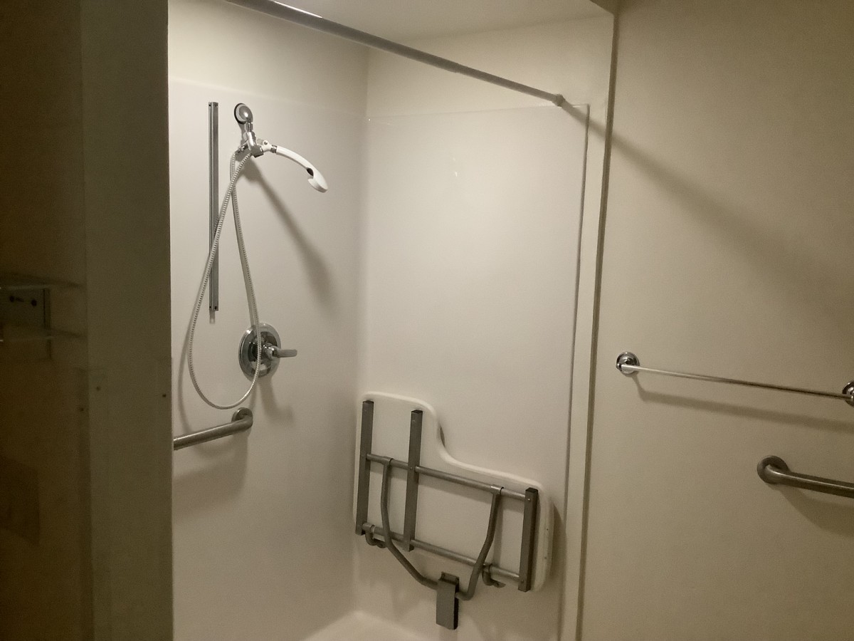 An accessible shower with handrails and a foldable seat.