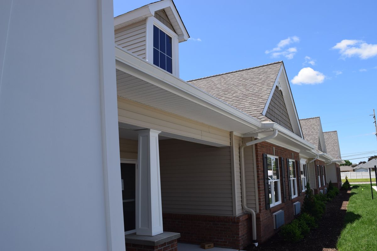 A residential house with a pitched roof and porch under a clear blue sky.