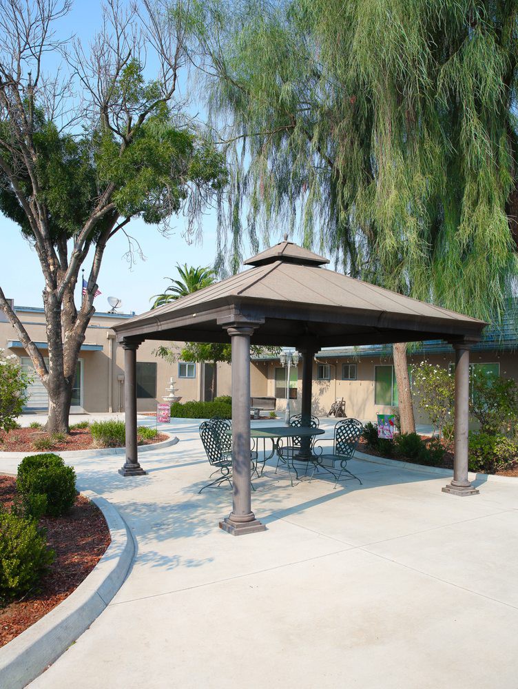 An outdoor patio area with a gazebo and furniture surrounded by trees.