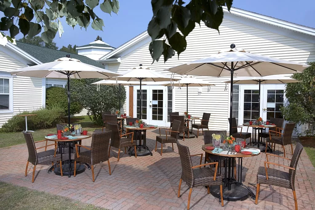 A sunny outdoor patio with tables, chairs, and umbrellas at a caf or restaurant.