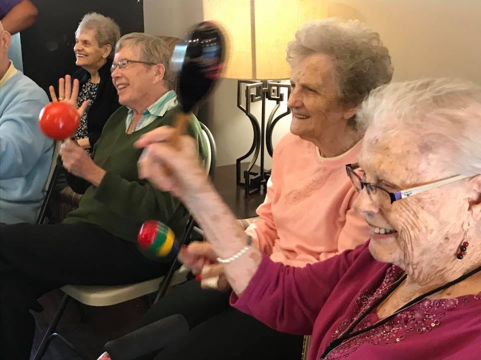 A group of elderly people enjoying a music activity with maracas.