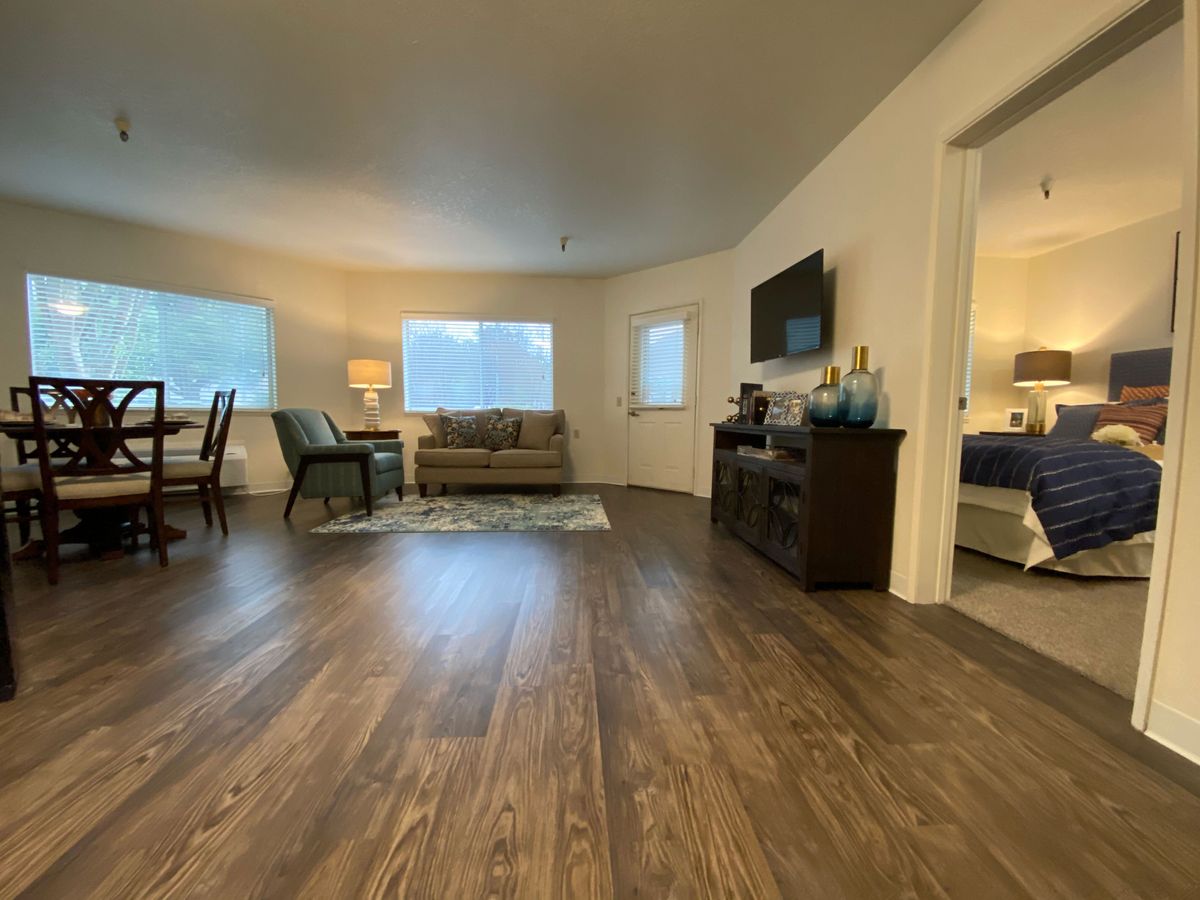 A spacious living room with a hardwood floor, modern furniture, and a dining area.