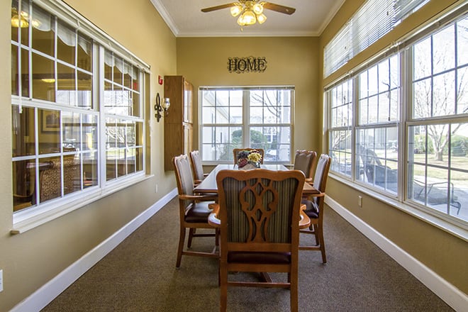 A cozy dining room with large windows and a ceiling fan.