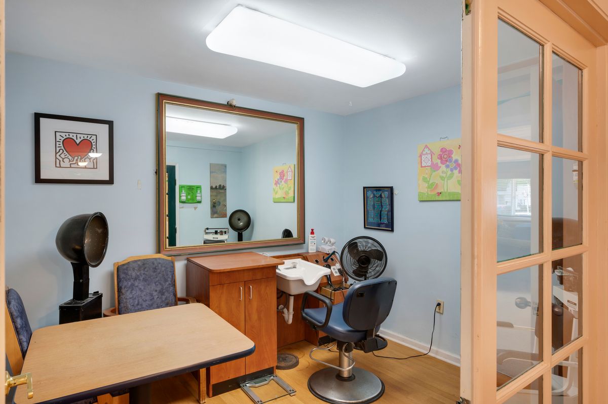 Interior of a small hair salon with a mirror, chair, and desk.