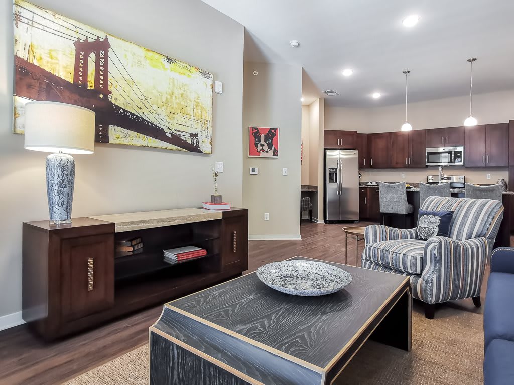 A modern living room with an open layout leading into the kitchen, featuring stylish furniture and artwork.
