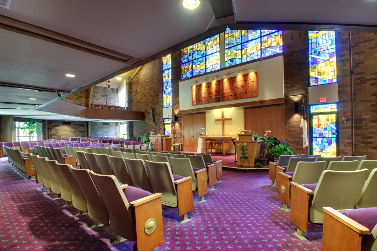Interior view of a church with stained glass windows and pews.
