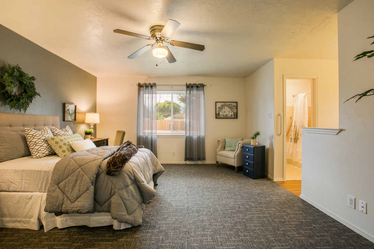 A cozy bedroom with a large bed, ceiling fan, and stylish decor.