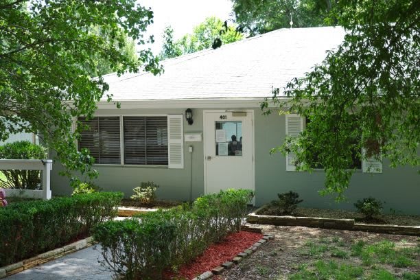 A cozy single-story house with a landscaped front yard surrounded by trees.