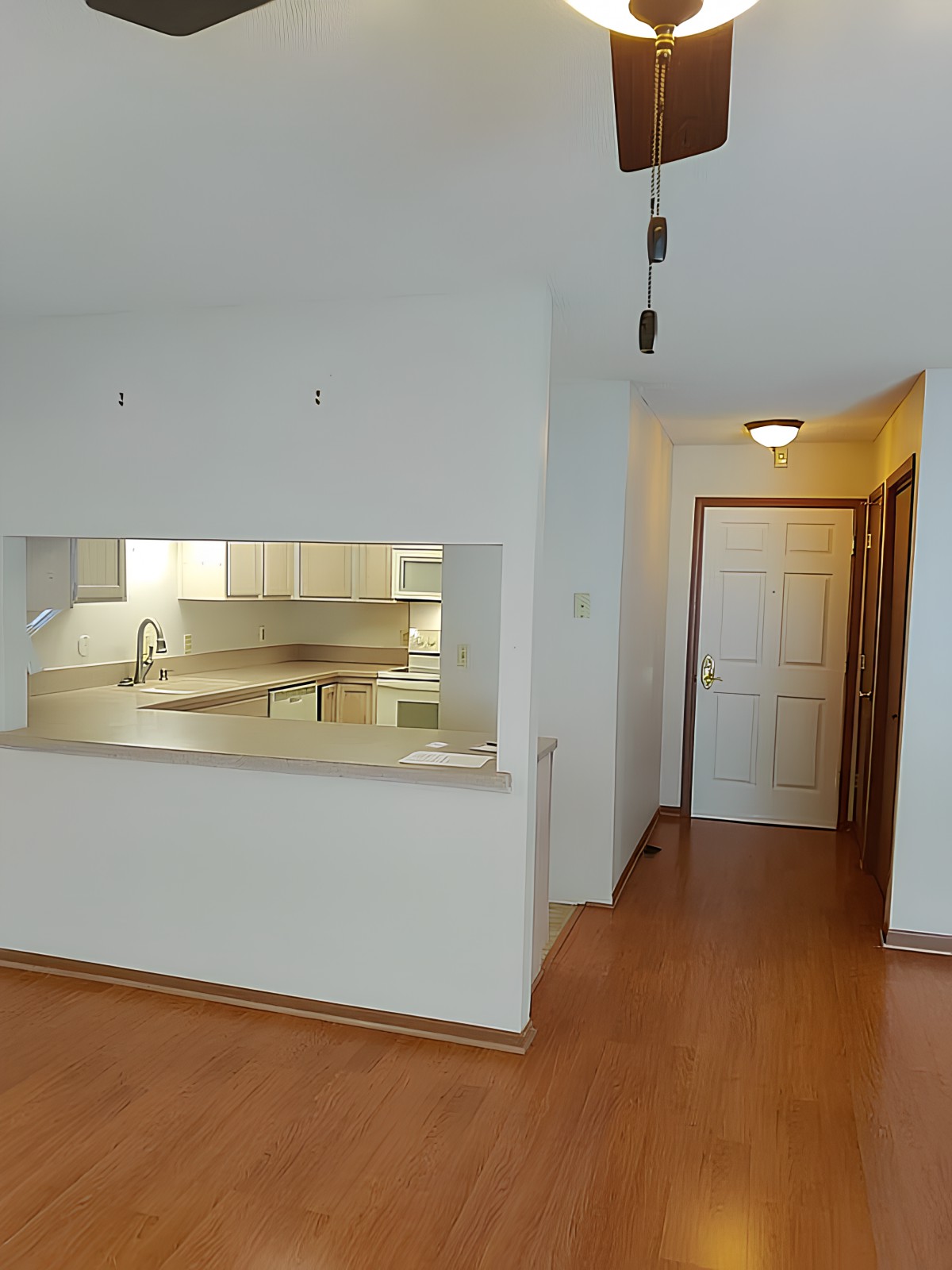 A modern apartment interior featuring a kitchen with an open counter and wood flooring.