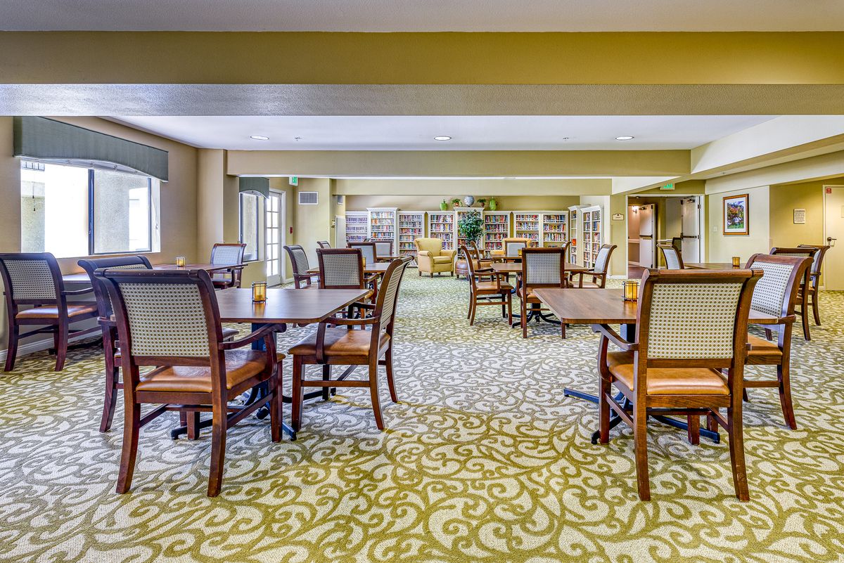 A spacious dining area with neatly arranged tables and chairs, featuring a patterned carpet.