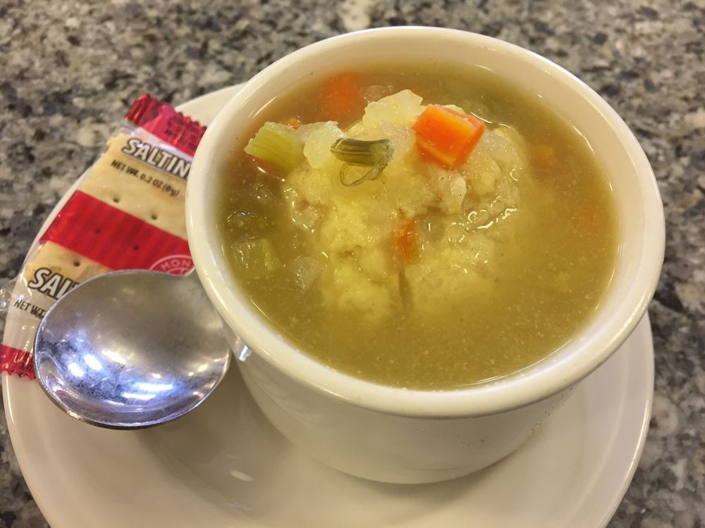 A bowl of vegetable soup served with crackers.