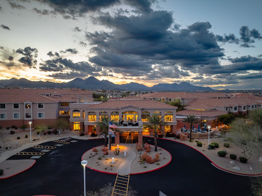 A picturesque view of a hotel at sunset, surrounded by mountains and dramatic clouds.