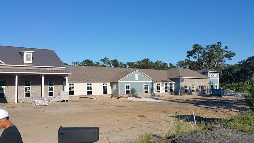 A newly constructed residential building surrounded by an unfinished landscape under a clear blue sky.