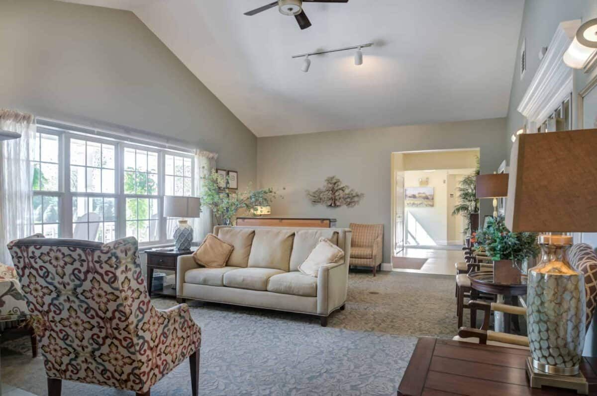 A cozy living room with a sofa, patterned chair, and large windows letting in natural light.