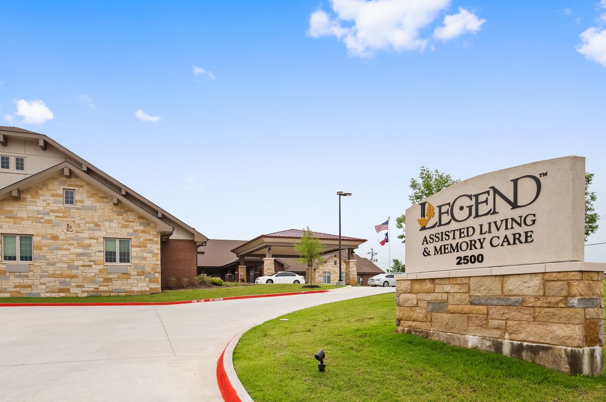 A view of an assisted living and memory care facility with its sign displayed at the entrance.