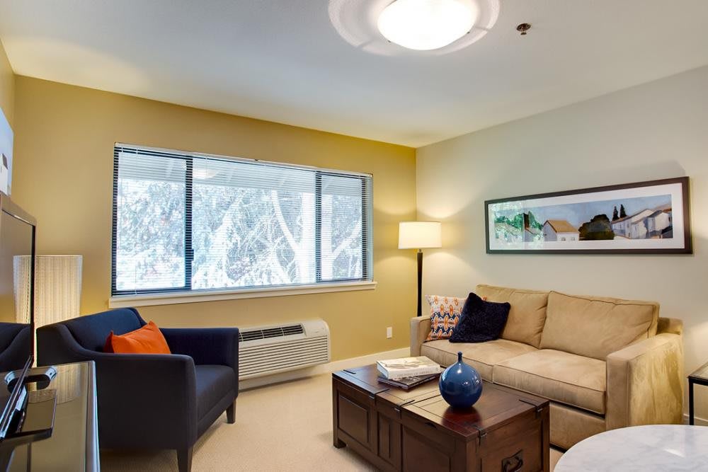 A cozy living room with a sofa, coffee table, and large window.