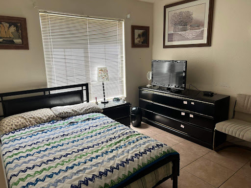 A cozy bedroom featuring a striped bedspread, modern furniture, and a large window.