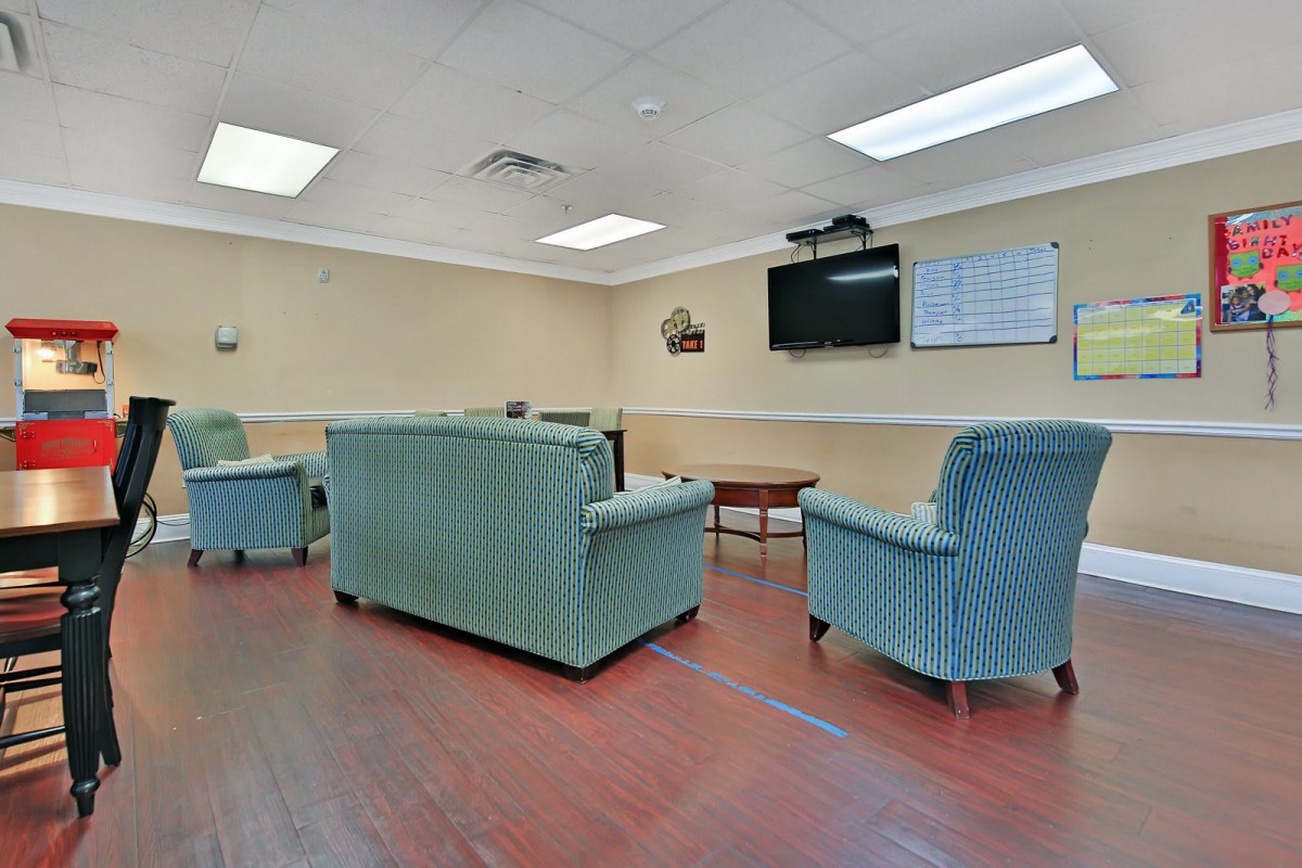 A cozy waiting room with comfortable chairs and a television on the wall.