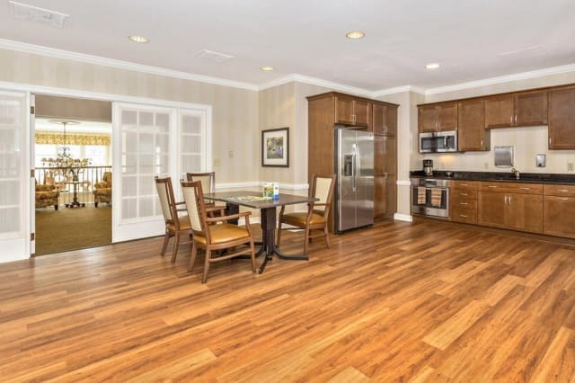A modern kitchen with a wooden dining set and sleek appliances.