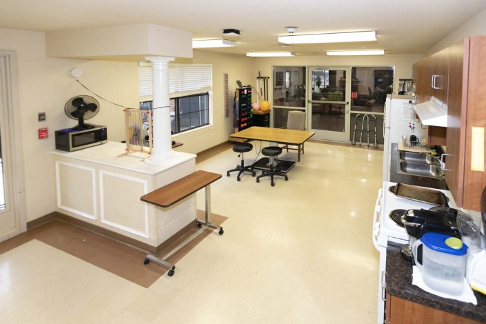 A modern and clean kitchen interior with tables, chairs, and cabinetry.