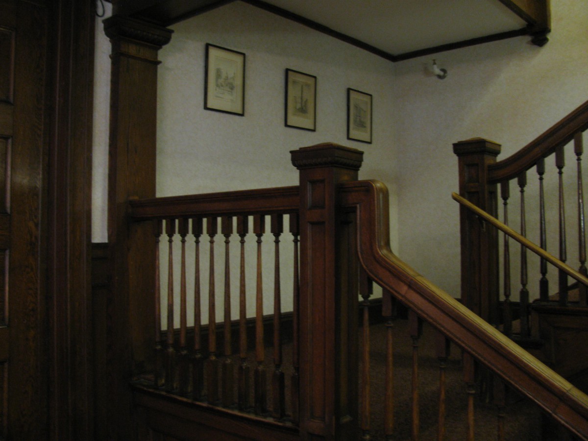 A vintage wooden staircase with framed artwork on the wall.