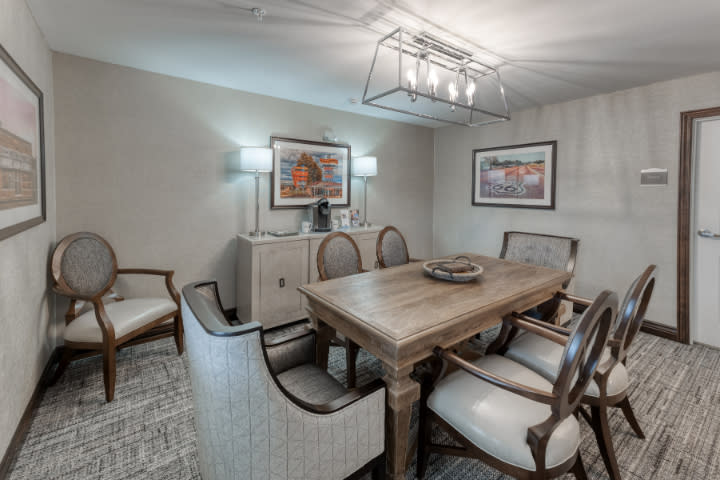 A stylish dining room featuring a wooden table, upholstered chairs, and modern lighting.